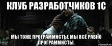 a man is hugging another man in a dark room with russian writing .