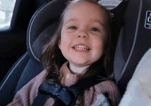 a little girl is smiling while sitting in a car seat that says 10