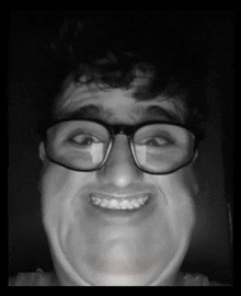 a man wearing glasses is smiling and making a funny face