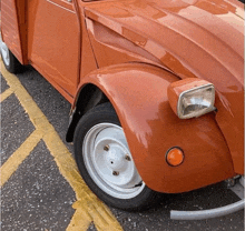 an orange car is parked in a parking lot with yellow lines