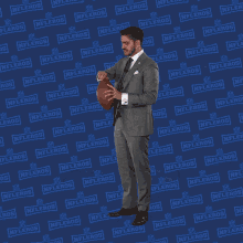 a man in a suit is holding a football in front of a nflers logo