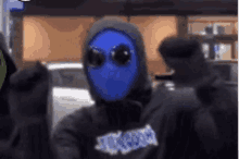 a person wearing a blue mask and sunglasses is standing next to another person .