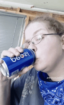 a woman wearing glasses is drinking from a blue pepsi can