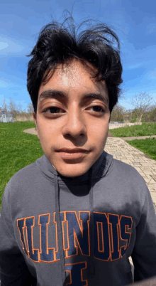 a young man wearing a gray illinois sweatshirt looks at the camera