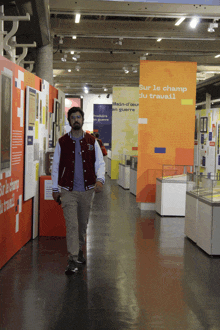 a man in a varsity jacket walks through a museum