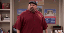 a man in a red shirt is standing in front of a wall with posters for the legislative branch and the judicial branch