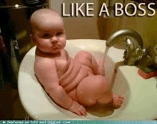 a baby is sitting in a sink with water pouring out of it .