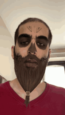 a man with a beard and face paint has a tattoo on his forehead