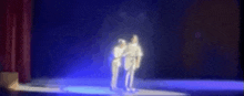 a blurry picture of two people on a stage with blue lights behind them .