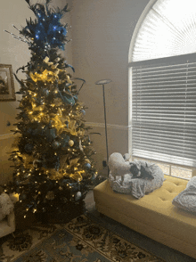 a christmas tree in a living room with a yellow ottoman