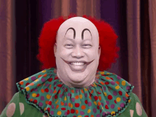 a bald clown with red hair is smiling and wearing a green polka dot collar