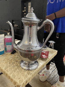 a silver teapot sits on a table next to a bottle of maybelline moisturizing lotion