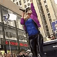 a woman is standing on a stage in front of a crowd holding a bottle of beer in her hand .