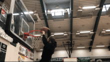 a man dunks a basketball in front of a sign that says grizzlies on it