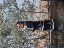 a woman in a black dress is standing in front of trees