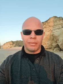 a bald man wearing sunglasses and a plaid shirt