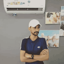 a man wearing a champion shirt stands in front of a wall with pictures on it