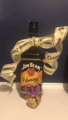 a bottle of jim beam honey next to a toy bee with googly eyes