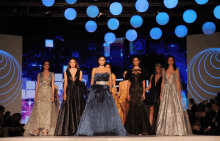 a group of women walking down a runway wearing dresses