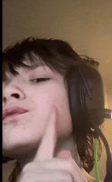 a woman wearing headphones and giving a thumbs up