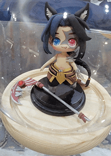 a statue of a girl with red eyes and a scythe on a wooden table