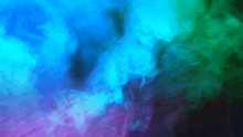 a blue , green and purple smoke coming out of a bottle on a dark background