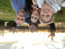 a family posing for a picture with their heads upside down in front of a lake