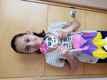 a girl wearing a striped shirt is holding a paper skeleton