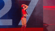 a woman in a red top and black shorts is standing on a stage