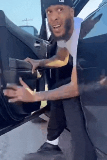 a man with a beard is getting out of a car with his hands out .