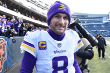 a vikings player wears a purple hat and a white jersey