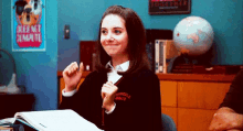 a woman is sitting at a desk in a classroom with a pencil in her hand and a globe in the background .