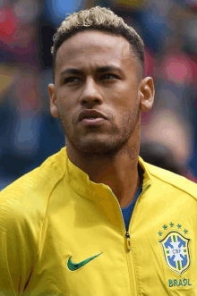 a close up of a man wearing a yellow jacket that says brasil