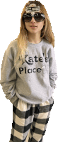 a woman wearing sunglasses and a kate 's place sweatshirt