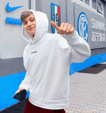 a man wearing a white hoodie is standing in front of a sign that says soning