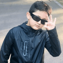 a boy wearing sunglasses and a jacket that says kipsta on it