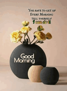 a black vase with yellow flowers and the words good morning