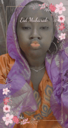 a woman wearing a purple scarf blowing a kiss with the words eid mubarak above her