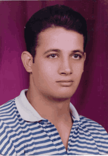 a man wearing a blue and white striped shirt is looking at the camera