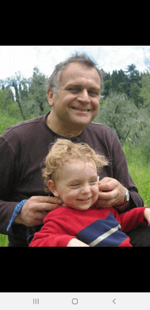 a man in a brown shirt is holding a little boy in a red shirt