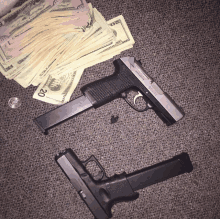 a stack of 20 dollar bills and two guns