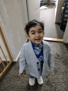 a little boy wearing a suit and tie is smiling for the camera