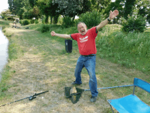 a man wearing a red shirt that says teamgeist is standing next to a fishing rod