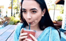 a woman is drinking a smoothie through a straw .