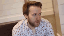 a man with a beard wearing a floral shirt