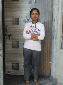 a woman wearing an aloha shirt stands in front of a door with her arms crossed