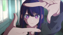 a girl with purple hair and pink eyes is being framed by a person 's hands