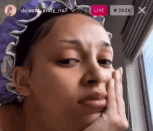 a woman wearing a purple shower cap is looking out a window .