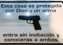 a sign that says " esta casa es protegida por dios y un arma " with a picture of a gun