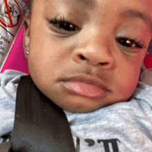 a close up of a baby 's face with a seat belt around his neck